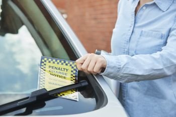 Close Up Of Female Motorist Looking At Parking Ticket