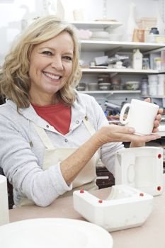 Portrait Of Mature Woman In Pottery Studio Casting Mug