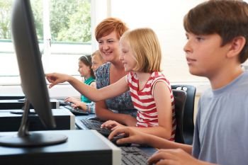 Female Elementary Pupil In Computer Class With Teacher