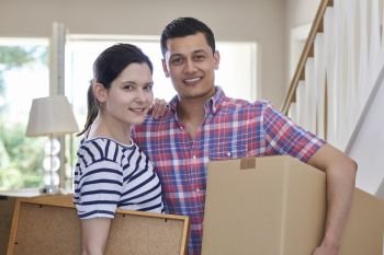 Portrait Of Couple Carrying Boxes Into New Home On Moving Day