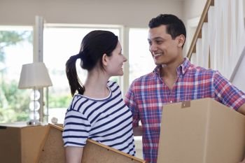 Young Couple Carrying Boxes Into New Home On Moving Day