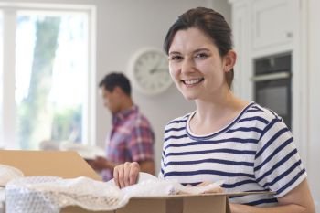 Portrait Of Young Couple Unpacking Boxes In Kitchen On Moving Day