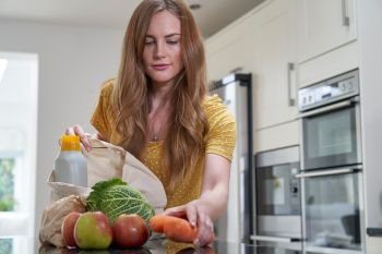 Woman Returning Home From Shopping Trip Unpacking Plastic Free Grocery Bags                               