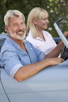 Mature Couple Enjoying Road Trip In Classic Open Top Sports Car Together                             