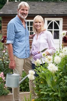 Portrait Of Mature Couple Working In Flower Beds In Garden At Home             
