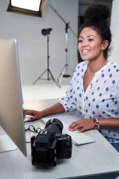 Female Photographer In Studio Reviewing Images From Photo Shoot On Computer                          