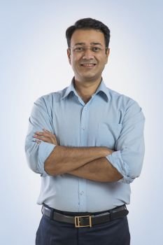 Portrait of a smiling businessman in eyeglasses standing with arms crossed