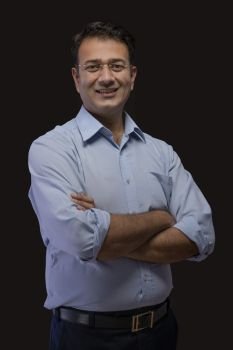 Portrait of a smiling businessman in eyeglasses standing with arms crossed against a black background