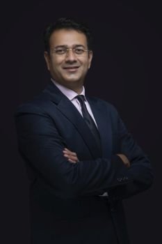 Portrait of a smiling businessman in eyeglasses standing with arms crossed