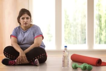 Depressed overweight woman sitting on the floor and doesn't wont to exercise