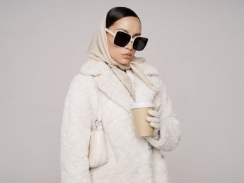 Beautiful young lady in a stylish white outfit. Refined taste. Elegance. Old money style. White faux fur coat
