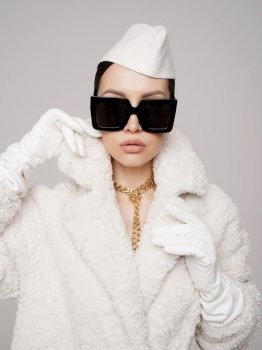 Beautiful young lady in a stylish white outfit. Refined taste. Elegance. Old money style. White faux fur coat