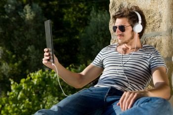 young man listening music with headphones, outdoor