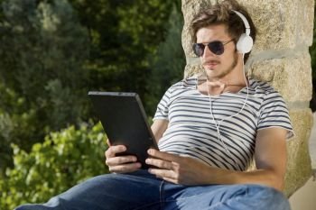 young man listening music with headphones, outdoor