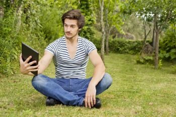 young man relaxing with a tablet pc, on a the park, outdoor