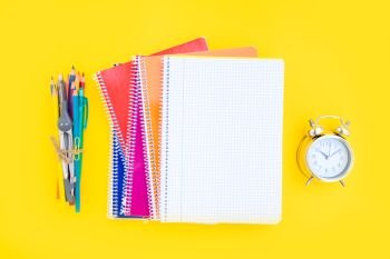 back to school concept minimal and creative flat lay scene on yellow background with copy space on empty sheet of notebook. back to school