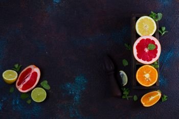 Orange, lemon and grapefruit with citrus reamer, copy space on dark textured background. Orange, lemon and grapefruit