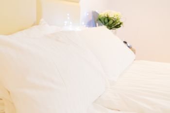 view of bed with white linen and pillows close up. bedroom interior closeup