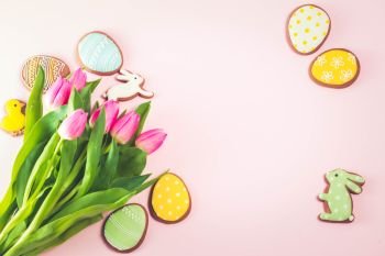 Eater handmade cookies with tulip flowers bouquet on pink background, retro toned. Easter scene with colored eggs
