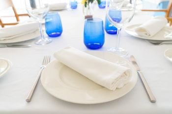 Served table setting with white plates and blue glasses. Served table with plates