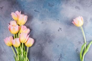 Frame of pink and yellow tulips on gray stone background. Pink and yellow tulips