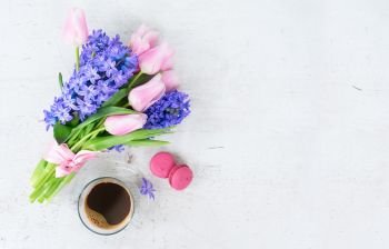Pink tulips and blue hyacinths flowers with cup of coffee on white wooden table with copy space. hyacinths and tulips