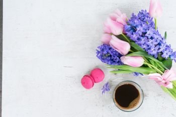 tulips and hyacinths fresh flowers with cup of coffee, holiday breakfast, copy space on white wooden background. hyacinths and tulips