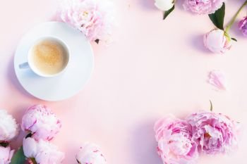 Beautiful fresh pink and white peony flowers on pink table with cup of coffee, frame with copy space for your text, top view and flat lay background. Fresh peony flowers