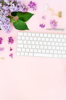 Flat lay top view home office workspace - modern keyboard with lilac flowers and copy space on desk. Top view home office workspace