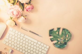Flat lay home office workspace - modern white keyboard with and peony flowers, copy space on pink background, toned. Top view home office workspace