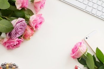 Styled flat desktop scene with mobile and flowers, copy space on white table. Styled desktop scene