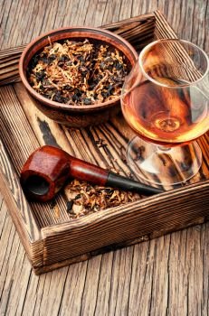 Smoking pipes and cognac on vintage style. Tobacco pipe and whiskey