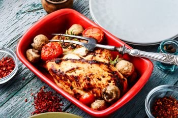 Baked chicken with mushrooms in a baking dish. Grilled chicken in baking dish