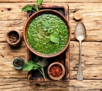 Nettle cream soup on wooden background.Soup with fresh nettles. Russian traditional nettle soup