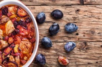 Meat stew with plums on rustic wooden background. Beef stew meat