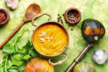 Vegetarian autumn pumpkin cream soup.Pumpkin soup and pumpkins. Pumpkin soup in a metal pot