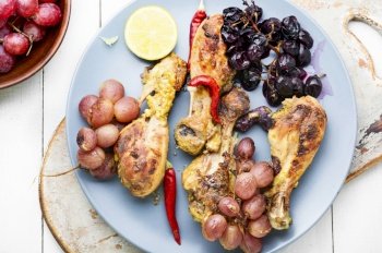 Baked chicken legs with grapes on white background. Baked chicken drumsticks