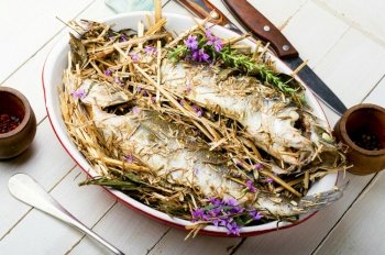 Fish baked in herbs and meadow hay. Roasted sea bass. Seabass fish baked with spicy herbs