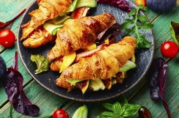 Croissant or sandwich with salted filling.Croissants with trout, meat bacon, vegetables and fruits. Croissant sandwich with meat and fish filling