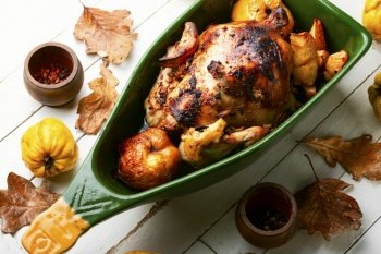 Homemade chicken baked with apples in baking tray.. Whole chicken roasted with autumn quince