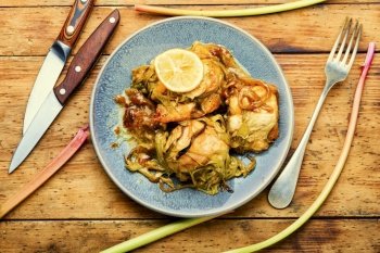 Delicious roasted chicken meat with rhubarb stalks. Chicken breast with rhubarb sauce.. Chicken meat baked with rhubarb,wooden table