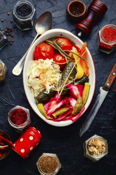 Pickled cucumbers, okra, bell peppers, tomatoes and sauerkraut in bowl. Appetizing pickles. Top view. Pickled vegetables and sauerkraut.