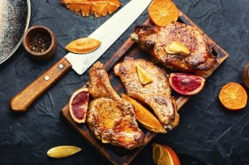 Roasted delicious meat in orange sauce. Pork on the bone. Meat grilled with citrus fruits