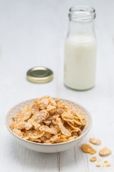 Cornflakes in a bowl and milk bottle.. Cornflakes in a bowl and milk bottle