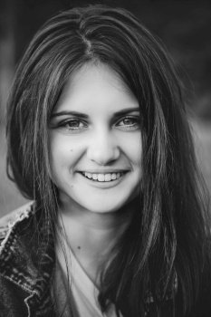 black and white portrait of a smiling teenage girl with long hair on a nature background. Portrait of a teenage girl with long hair