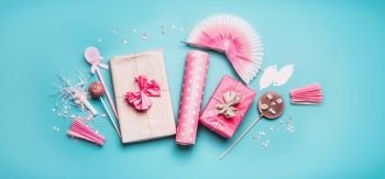 Pink holidays party accessories : gift boxes with ribbon, wrapping paper, chocolate lolly pops , party fan and decor on pastel blue background, top view, flat lay, banner