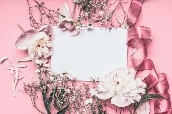 Flowers and petal arrangement around blank paper on pink background with ribbons, top view. Love feeling letter.  Instagram style. Wedding invitation. Mother’s Day. Greeting concept. Flat lay