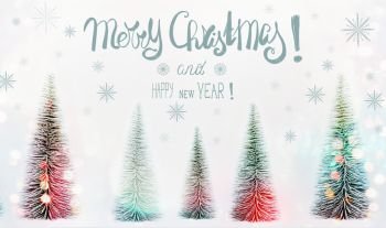 Merry Christmas and Happy New Year greeting card with text lettering, fir trees forest and sunshine bokeh, painted snowflakes on white background