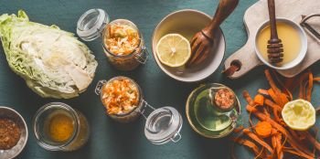 Chopped cabbage salad in jars for healthy lunch with ingredients on kitchen table background, top view, with copy space. Vegetarian food, low-calorie vegetable eating and weight loss dieting