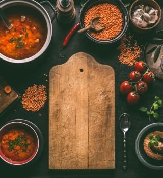 Cutting board food background of healthy vegan lentil dishes on dark kitchen table background with ingredients, top view. Vegetarian food. Clean diet eating. Source of plant based protein. Copy space